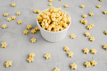 Breakfast cereals сosmostars in small white plate and a lot of stars around. Food for children 