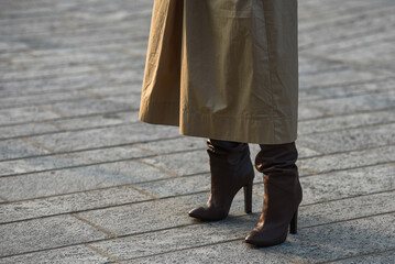 Detail of a fashionable outfit – woman wearing beige coat and high heel boots