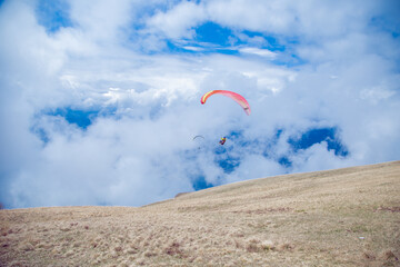 Two paragliders flying in the clouds near lake Garda. Italy