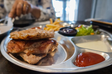 Pork steak with fries and vegetables on the food tray