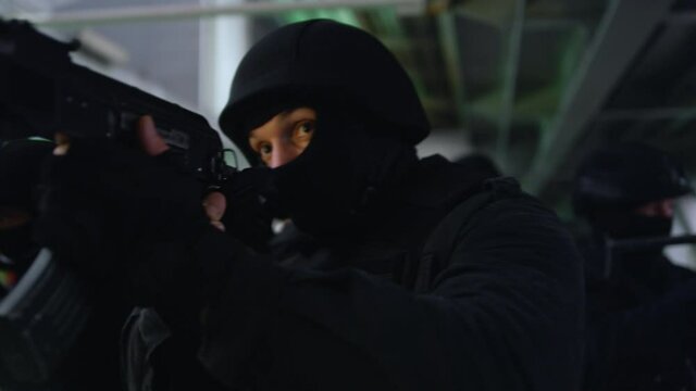 Masked military soldiers targeting scopes on rifles. SWAT team exploring bridge 