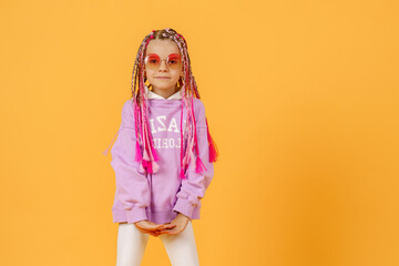 Stylish girl in rounded glasses with pink dreadlocks posing on a