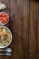 pilaf, salad, bread and a branch of basil on a wooden table
