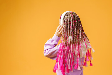 Back view of Adorable child in rounded glasses with pink dreadlo