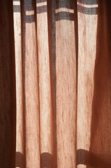 hazel-beige or tan curtains backlit featuring undulating shadows and highlights - vertical theme
