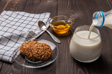 Obraz na płótnie Canvas breakfast with oatmeal cookies with cereals and milk poured from a bottle into a glass