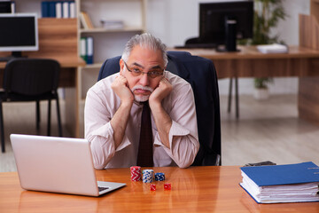 Obraz premium Old male employee in gambling concept at workplace
