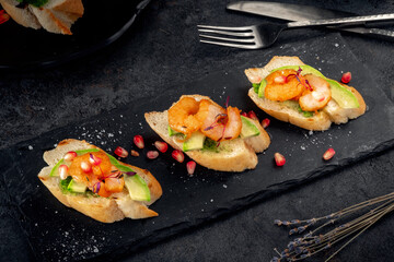 Set Bruschetta with fried shrimp, avocado and sesame seeds. Italian antipasti on a white baguette.