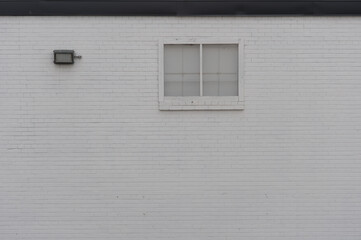 painted white brick wall, featuring a window and a safety light
