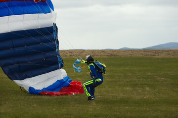 Skydiver tries to extinguish the parachute canopy after landing in windy weather, close-up.
