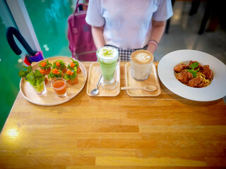 Set of food for lunch or dinner with glass of green tea and a cup of coffee, Spaghetti meat ball , Shushi roll on a wooden table and a woman with copy space for text.