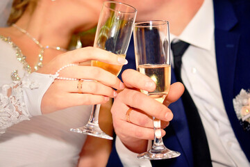 Glasses of champagne in the hands of the newlyweds close-up