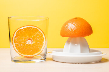 Closeup shot of freshly cut oranges in a glass next to a juicer on a wooden surface