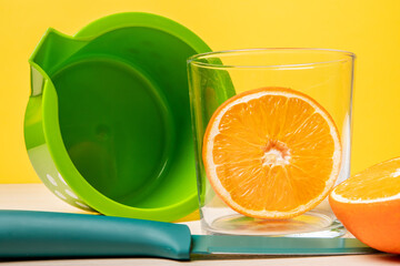 Closeup shot of freshly cut oranges in a glass next to a juicer