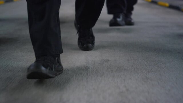 Special forces team feet moving towards camera on road. Men wearing black shoes