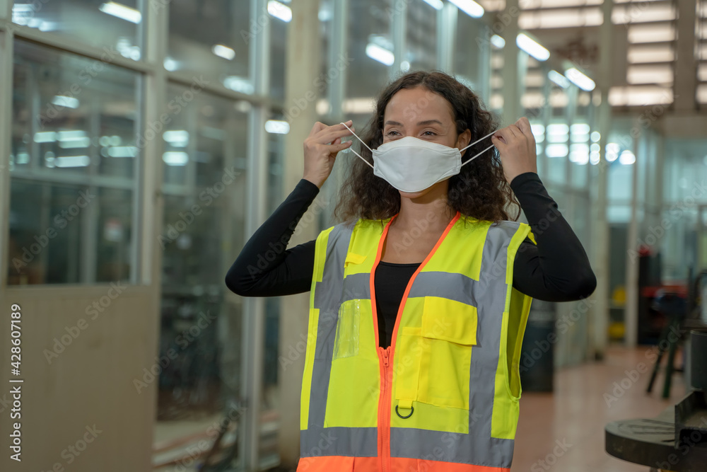 Poster engineer woman wearing protection face mask working and checking machine in the factory.