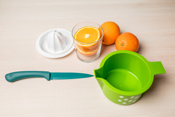 Closeup shot of freshly cut oranges in a glass next to a juicer on a wooden surface