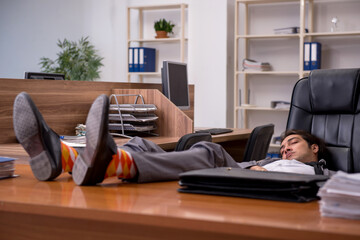 Young male employee sleeping at workplace