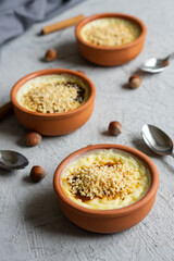 Baked rice pudding turkish milky dessert sutlac in casserole with cinnamon sticks and chopped hazelnuts