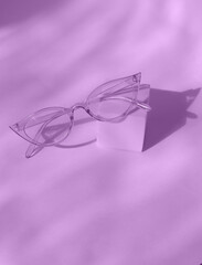 Sunglasses on square podium in trendy violet color background.