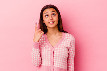 Young Indian woman isolated on pink background indicates with both fore fingers up showing a blank...