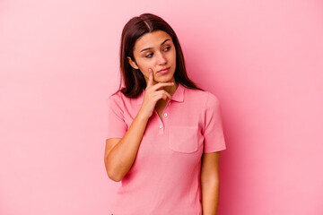 Young Indian woman isolated on pink background contemplating, planning a strategy, thinking about the way of a business.