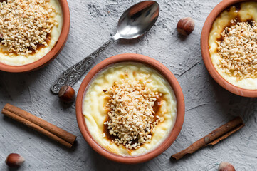 Baked rice pudding turkish milky dessert sutlac in casserole with cinnamon sticks and chopped hazelnuts