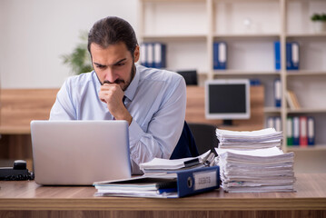 Obraz premium Young businessman employee unhappy with excessive work in the of