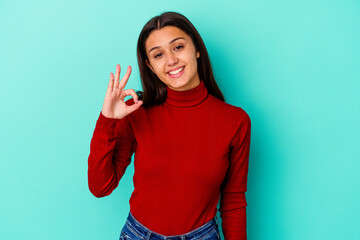 Young Indian woman isolated on blue background cheerful and confident showing ok gesture.
