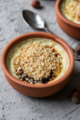 Baked rice pudding turkish milky dessert sutlac in casserole with cinnamon sticks and chopped hazelnuts