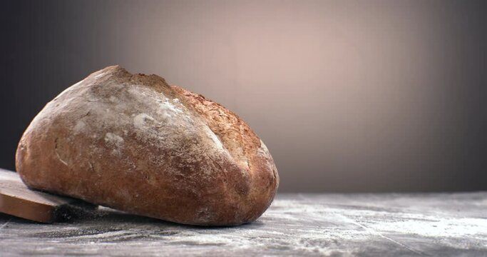 SUPER SLOW MOTION Freshly baked loaf of bread falling on a table covered with flour. Shot with high speed camera at 420 FPS
