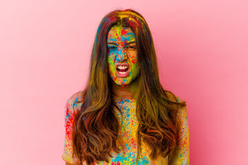 Young Indian woman celebrating holy festival isolated on white background screaming very angry and...