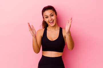 Young sport Indian woman isolated on pink background receiving a pleasant surprise, excited and raising hands.