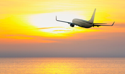 Fototapeta premium Airplane flying over tropical sea at amazing sunset
