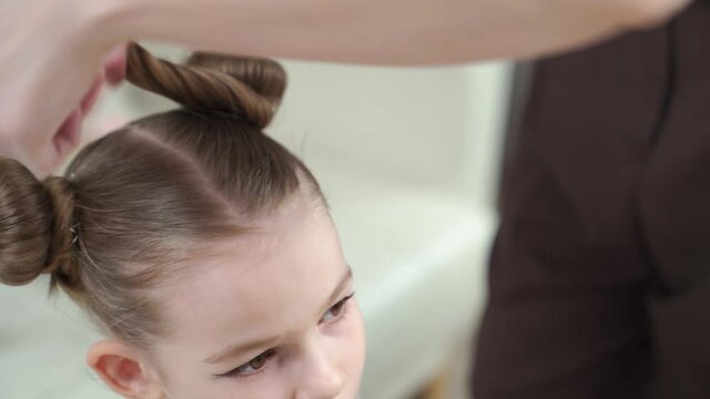 Mom makes a hairstyle her daughter. preparing the child for the performance on stage. eye makeup.