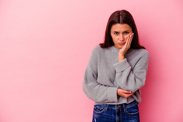 Young Indian woman isolated on pink background who feels sad and pensive, looking at copy space.