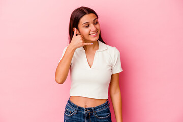 Young Indian woman isolated on pink background showing a mobile phone call gesture with fingers.