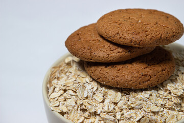 Oatmeal cookies on a plate with oatmeal on a white background. Diet food. Light breakfast