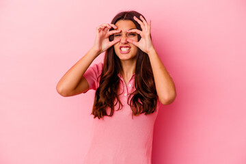 Young Indian woman isolated on pink background keeping eyes opened to find a success opportunity.