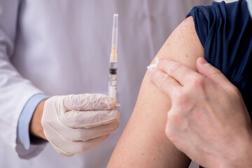 Old male patient visiting young male doctor in vaccination conce