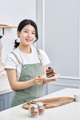 Asia Korean young woman serving a piece of chocolate cake on a plate