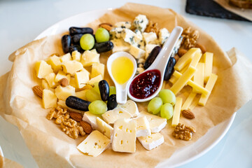 cheese, grapes, nuts, jam and honey on a plate. serving the table with appetizers and delicacies for the holiday. Catering.