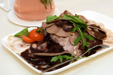 Cold cuts of meat on a plate. Appetizer of cold cuts on the dining table.