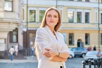 Fototapeta premium Outdoor portrait of young confident business woman with crossed arms