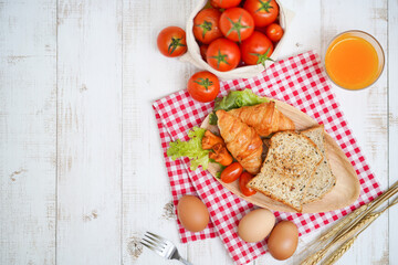 Breakfast. Set of healthy breakfast including toasts, croissant, sausages, eggs, sack of fresh tomatoes and a glass of orange juice on vintage white wood background with copy space for your text.