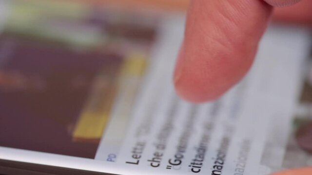 Scrolling news on smartphone screen with finger. Close up of smartphone action. News feed scroll