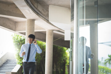 Attractive asian business man using mobile phone while walking in office building.