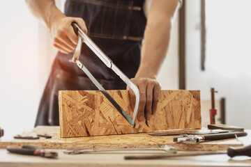 Male carpenter builder working with wooden board in the workshop to decorate the woodwork.
