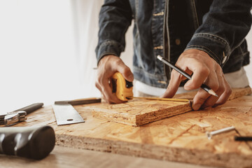 Male carpenter builder working with wooden board in the workshop to decorate the woodwork.