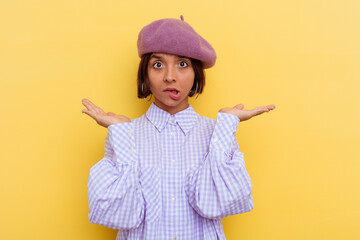 Young mixed race woman wearing a beret isolated on yellow background confused and doubtful...